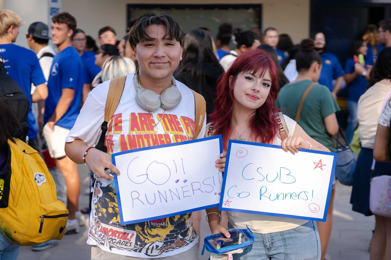 Two students holding up go runners sign
