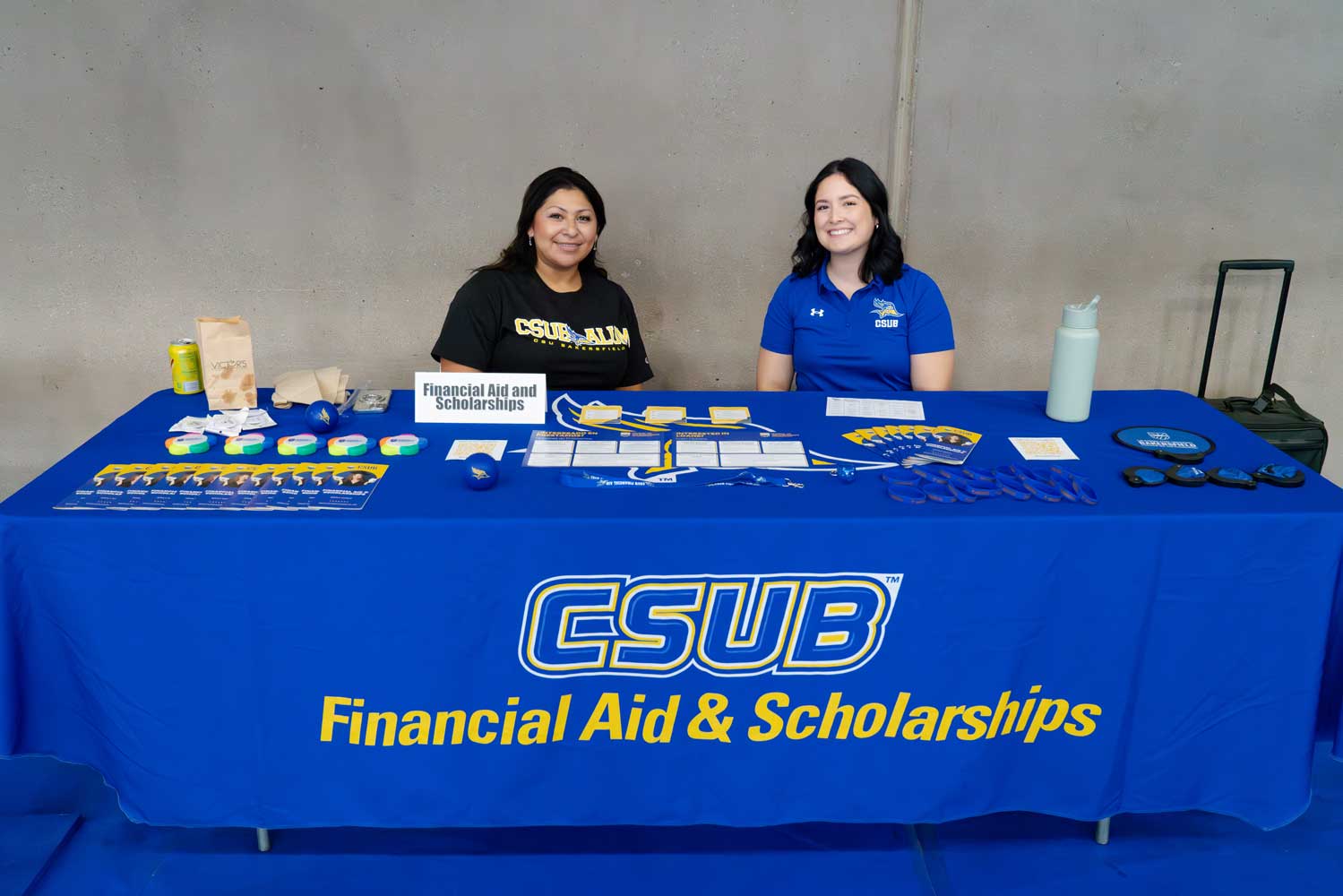 Two individual sitting at the Financial Aid & Scholarships table