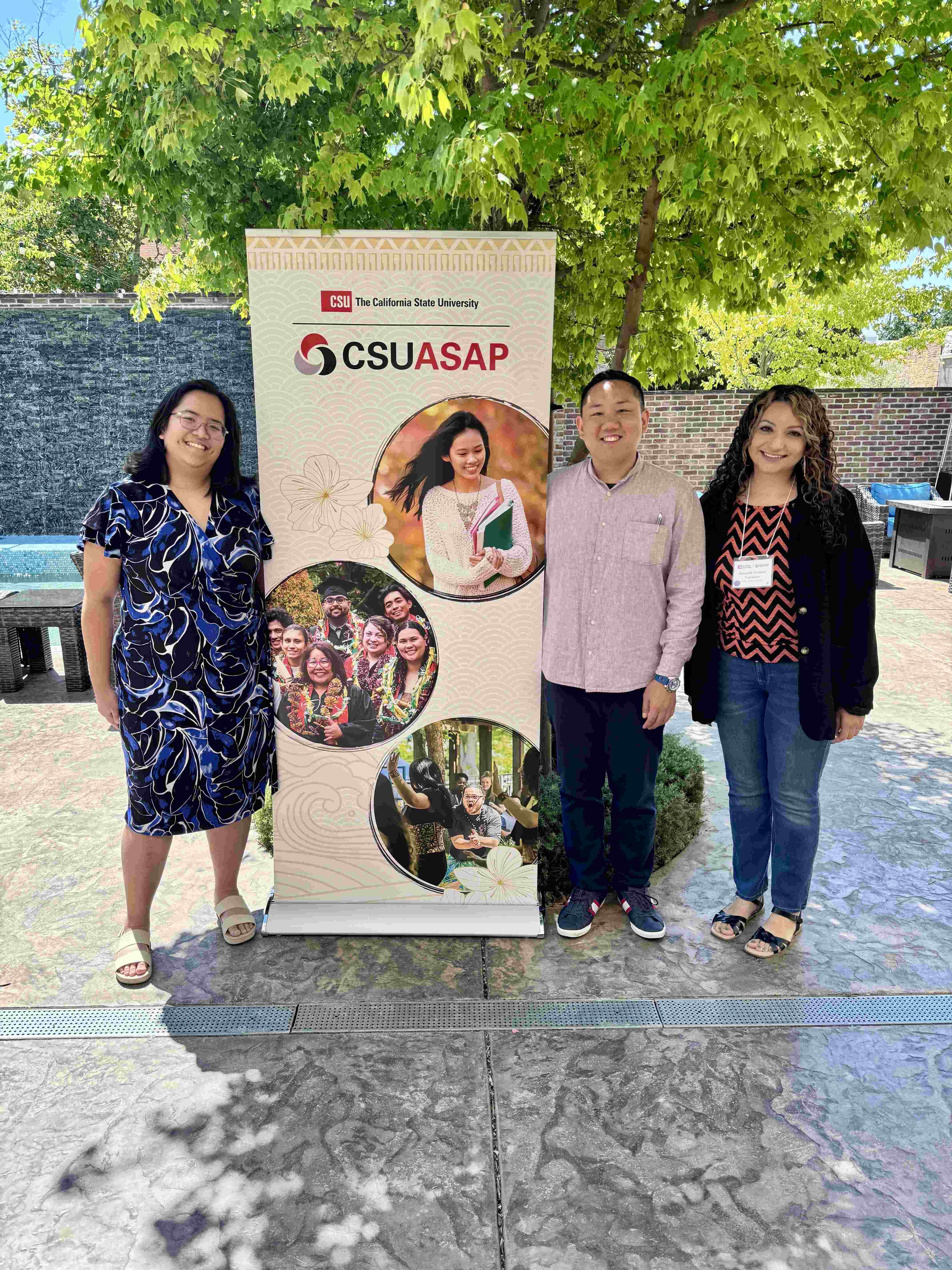 Three people standing next to a California State University Asian American, Native Hawaiian, and Pacific Islander Student Achievement Program, known as CSUASAP. People from left to right: Marrian Angeles, Mike Kwon, and Anayeli Gomez-Navarro