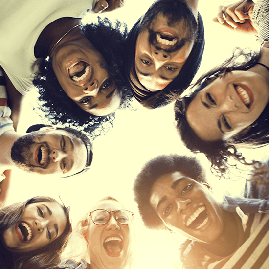 Group of students standing in a circle and looking down at camera