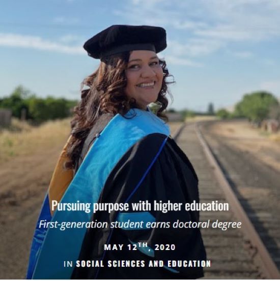 Woman in graduate attire standing on train tracks