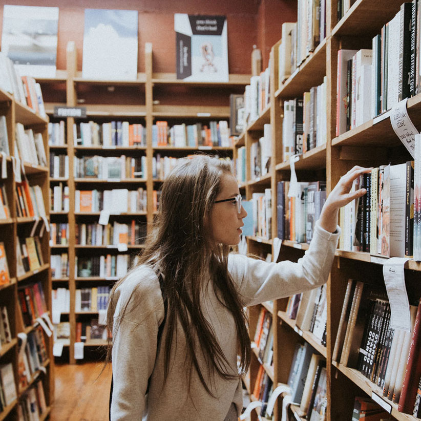 Woman in a library looking at books on a shelf