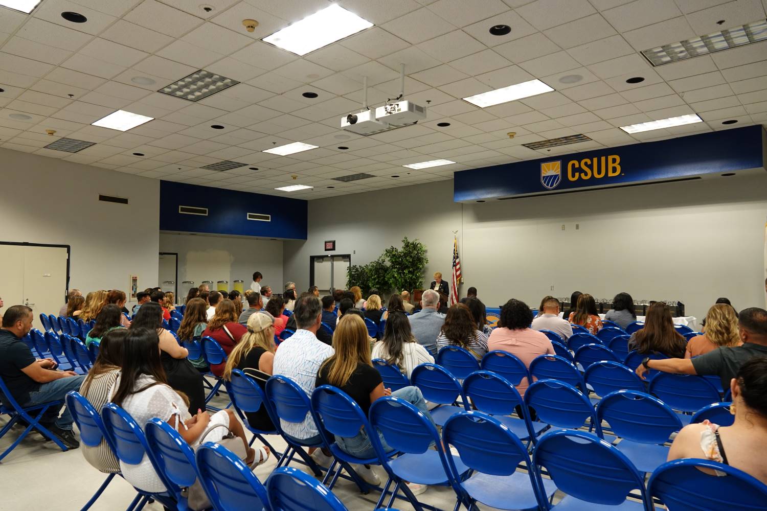 Group of people sitting in blue chairs during a presentation