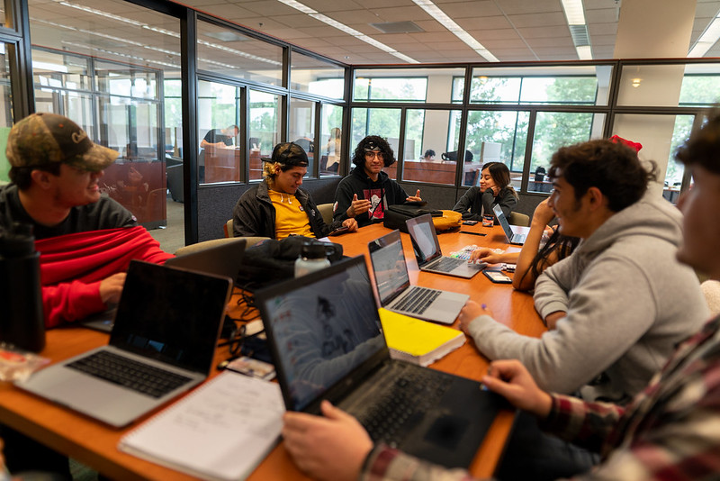 Study group sitting at a table and working on laptops