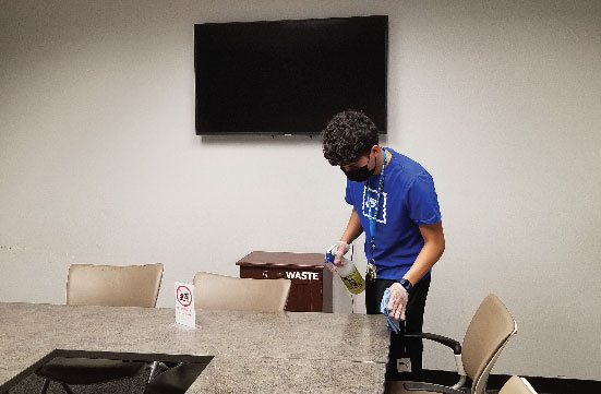 Facilities Assistant wiping down tables